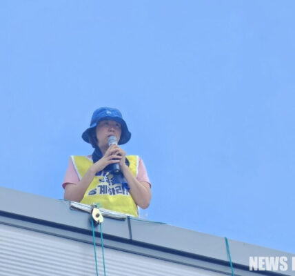 2025년 7월 26일, 한국옵티칼하이테크 공장 옥상에서 박정혜 수석부지회장이 565일째 고공농성을 이어가고 있다. 그는 열악한 환경 속에서도 해고 노동자들의 고용 승계를 요구하며 '세상에서 가장 슬픈 세계 신기록'을 쓰고 있다.