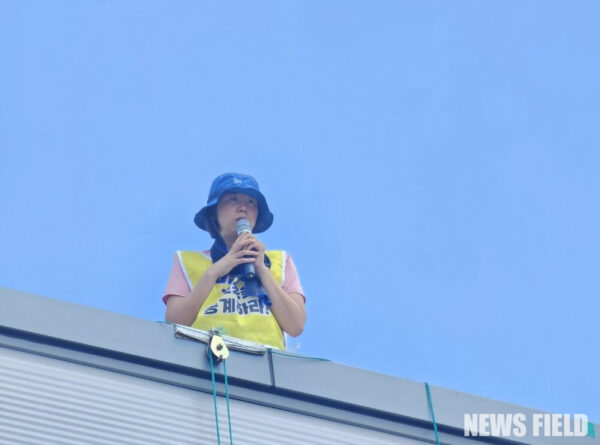 2025년 7월 26일, 한국옵티칼하이테크 공장 옥상에서 박정혜 수석부지회장이 565일째 고공농성을 이어가고 있다. 그는 열악한 환경 속에서도 해고 노동자들의 고용 승계를 요구하며 '세상에서 가장 슬픈 세계 신기록'을 쓰고 있다.