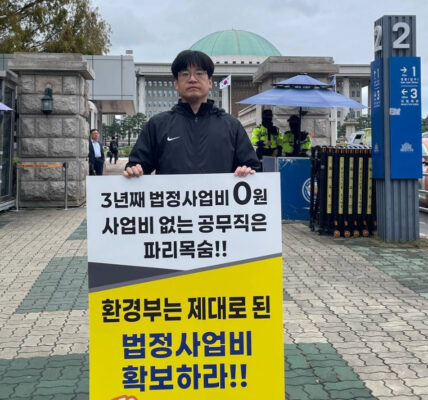 공공운수노조 4대강물환경연구소지회 소속 노동자가 13일 국회 앞에서 '임금체불과 강제휴업의 악순환을 멈추라'고 적힌 피켓을 들고 1인 시위를 진행하고 있다.