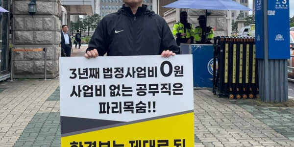 공공운수노조 4대강물환경연구소지회 소속 노동자가 13일 국회 앞에서 '임금체불과 강제휴업의 악순환을 멈추라'고 적힌 피켓을 들고 1인 시위를 진행하고 있다.