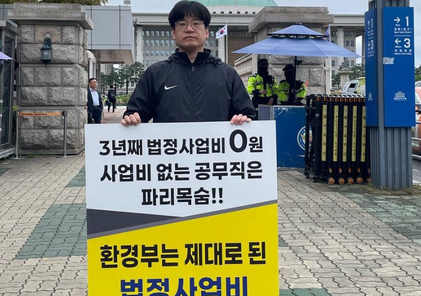 공공운수노조 4대강물환경연구소지회 소속 노동자가 13일 국회 앞에서 '임금체불과 강제휴업의 악순환을 멈추라'고 적힌 피켓을 들고 1인 시위를 진행하고 있다.