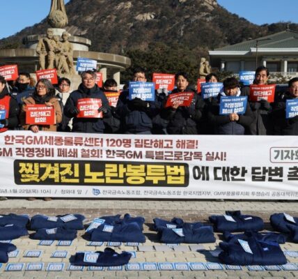 22일 오전 서울 청와대 앞 '한국GM 집단해고 해결 촉구 기자회견'에서 참가자들이 해고 노동자들의 작업복 위에 사원증을 놓는 퍼포먼스를 진행하며 고용승계 이행과 집단해고 철회를 촉구하고 있다.