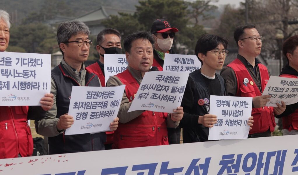 3일 오전 청와대 사랑채 앞에서 열린 기자회견에서 공공운수노조 관계자들이 택시사업자의 조세포탈 의혹을 규탄하며 '택시발전법 개정안 폐기'와 '월급제 쟁취' 문구가 적힌 피켓을 들고 구호를 외치고 있다.