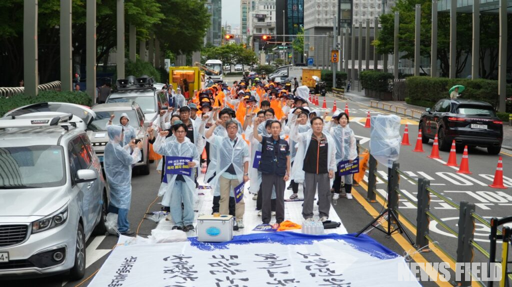 지난 14일 서울 서초동 삼성전자 사옥 앞에서 열린 결의대회에서 삼성화재애니카지부 조합원들이 세차게 내리는 빗속에서 우비를 입고 손피켓을 든 채 사측의 비대면 영상통화 사고 접수 폐지와 단체협약 이행을 요구하며 구호를 외치고 있다.
