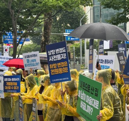 22일 서울 강남경찰서 인근에서 열린 집회에서 우비를 입은 '힐스테이트 더 운정' 수분양자들이 비를 맞으며 '상향 변경도 사전통지, 하향 변경은 전원동의', '설명 없는 동의서가 개별동의를 대신할 수 없다', '내 돈으로 산 집, 왜 남이 마음대로 바꿉니까' 등이 적힌 피켓을 들고 있다.