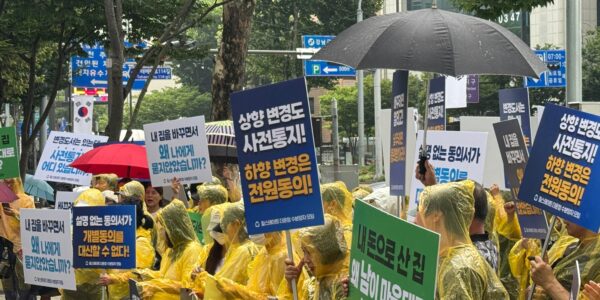 22일 서울 강남경찰서 인근에서 열린 집회에서 우비를 입은 '힐스테이트 더 운정' 수분양자들이 비를 맞으며 '상향 변경도 사전통지, 하향 변경은 전원동의', '설명 없는 동의서가 개별동의를 대신할 수 없다', '내 돈으로 산 집, 왜 남이 마음대로 바꿉니까' 등이 적힌 피켓을 들고 있다.