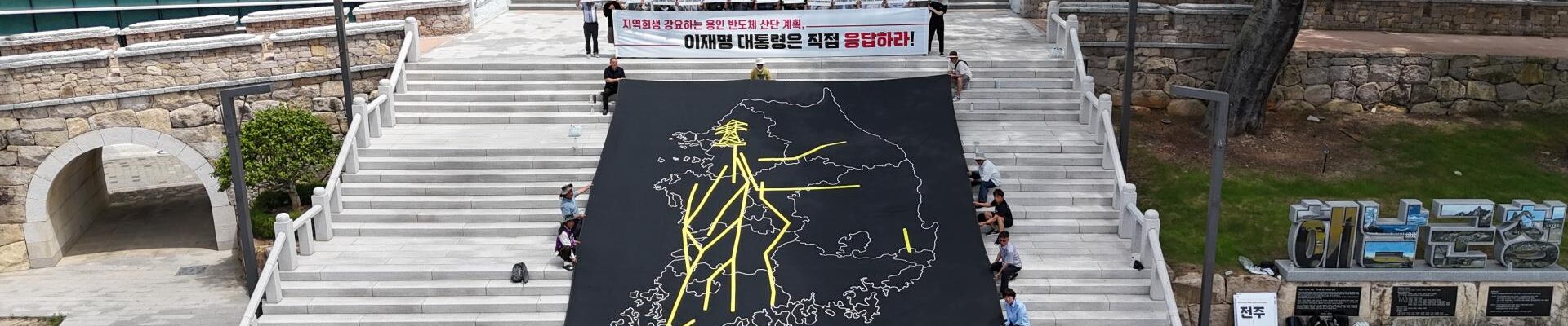30일 오전 전남 해남군청 앞 계단에서 열린 ‘용인 반도체 산단 재검토 및 초고압 송전탑 반대 전국 대행진’ 출정식에서 참가자들이 대한민국 지도 위에 초고압 송전선로 경유 노선을 표현한 대형 현수막을 펼치고 퍼포먼스를 진행하고 있다.
