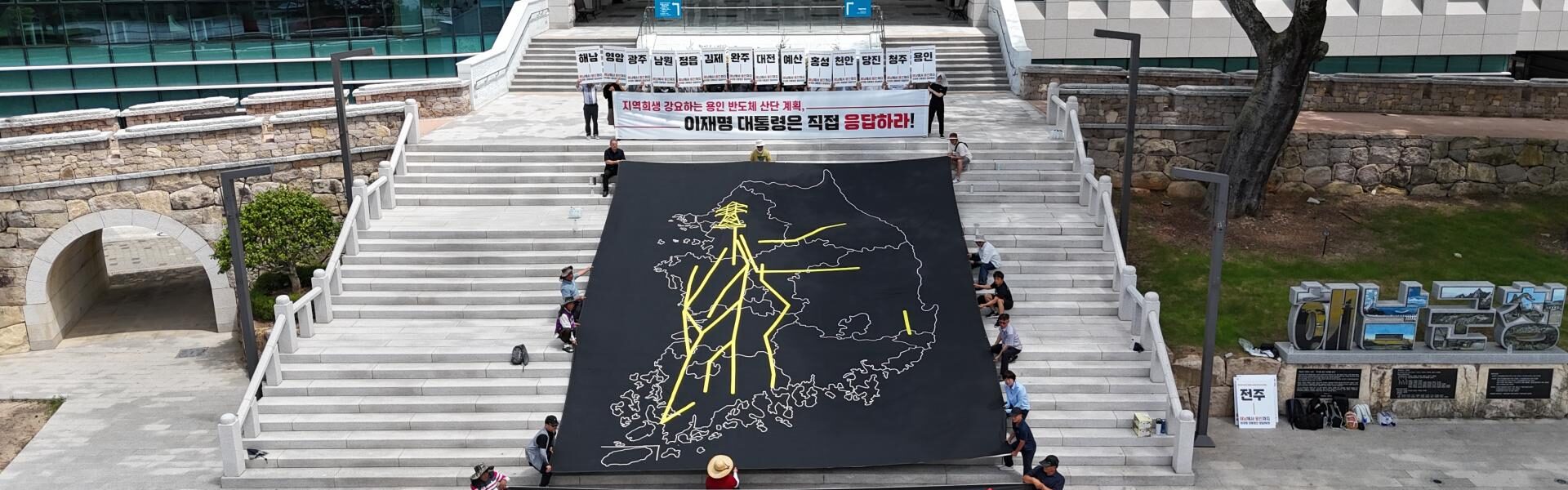 30일 오전 전남 해남군청 앞 계단에서 열린 ‘용인 반도체 산단 재검토 및 초고압 송전탑 반대 전국 대행진’ 출정식에서 참가자들이 대한민국 지도 위에 초고압 송전선로 경유 노선을 표현한 대형 현수막을 펼치고 퍼포먼스를 진행하고 있다.