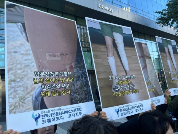 22일 서울 구로구 넷마블 사옥 앞 기자회견에서 코웨이 방문점검원들이 개에 물린 다리 상처 사진과 "코웨이는 더 이상 사고를 방치하지 마라"는 문구가 적힌 손팻말을 들고 있다. (출처=전국가전통신서비스노동조합)