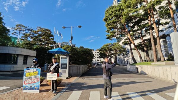 금속노조 충남지부 현대제철비정규직지회 조합원이 20일 서울 서초구 양재동 현대차그룹 본사 앞에서 "재벌총수 정의선! 비정규직 차별부터 해결하라!"라고 적힌 손팻말을 들고 시위하고 있다. 옆에서는 한 남성이 "노사관계 선진화로 기업경쟁력 강화"라고 적힌 팻말을 들고 서 있다. (출처=금속노조 충남지부 현대제철비정규직지회)
