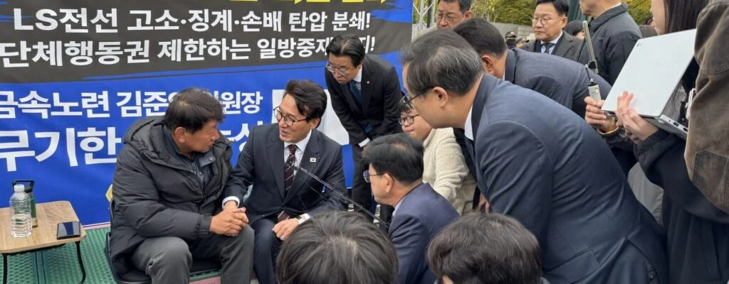29일 오전 LS전선의 부당노동행위 의혹 해결을 촉구하며 9일째 단식농성 중인 김준영 한국노총 금속노련 위원장(왼쪽)이 농성장을 방문한 김민석 더불어민주당 대표(가운데)와 손을 맞잡고 대화하고 있다. (사진=한국노총 금속노련 제공)