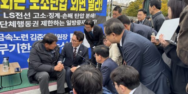 29일 오전 LS전선의 부당노동행위 의혹 해결을 촉구하며 9일째 단식농성 중인 김준영 한국노총 금속노련 위원장(왼쪽)이 농성장을 방문한 김민석 더불어민주당 대표(가운데)와 손을 맞잡고 대화하고 있다. (사진=한국노총 금속노련 제공)
